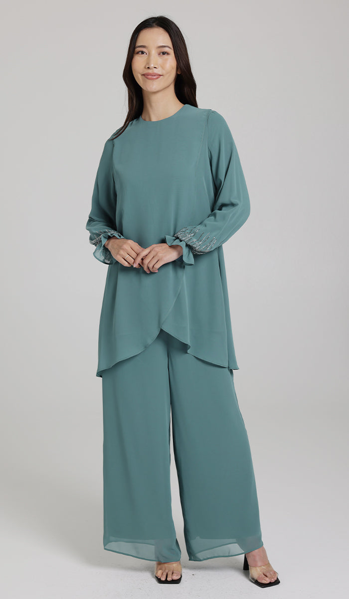 Woman wearing embellished tunic in Seagreen with pants and heels. 
