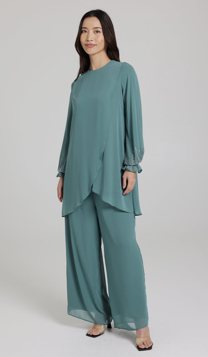 Woman wearing modest Seema tunic in Seagreen with pants and heels. 