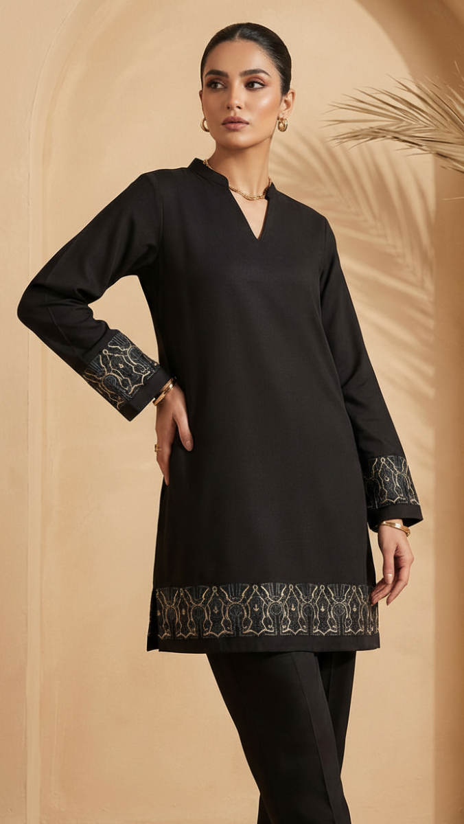 Woman wearing a black long-sleeve top with intricate designs on a beige background