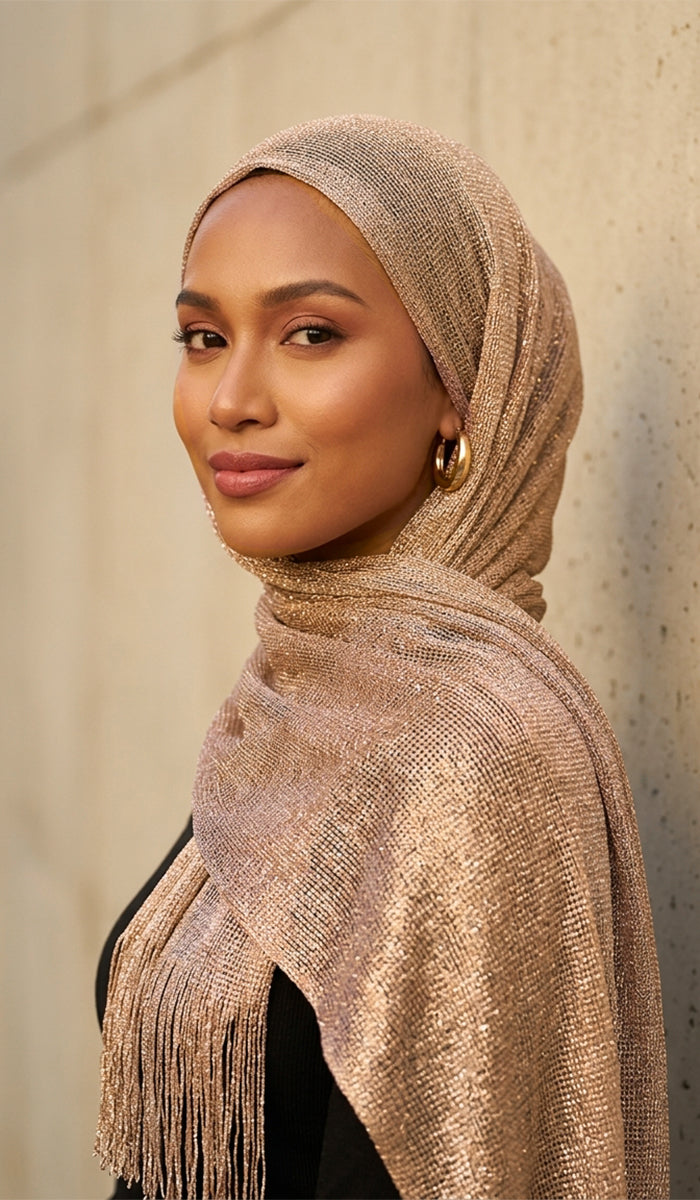 Woman wearing a beige hijab with fringe details against a neutral background