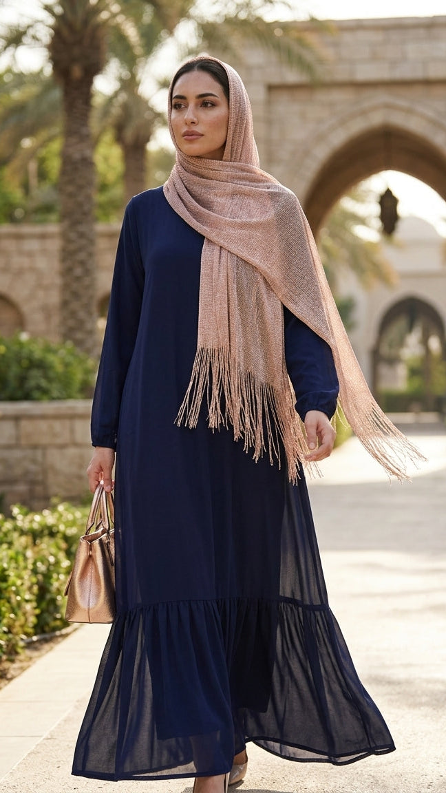 Woman in a navy blue dress with a beige scarf walking outdoors.