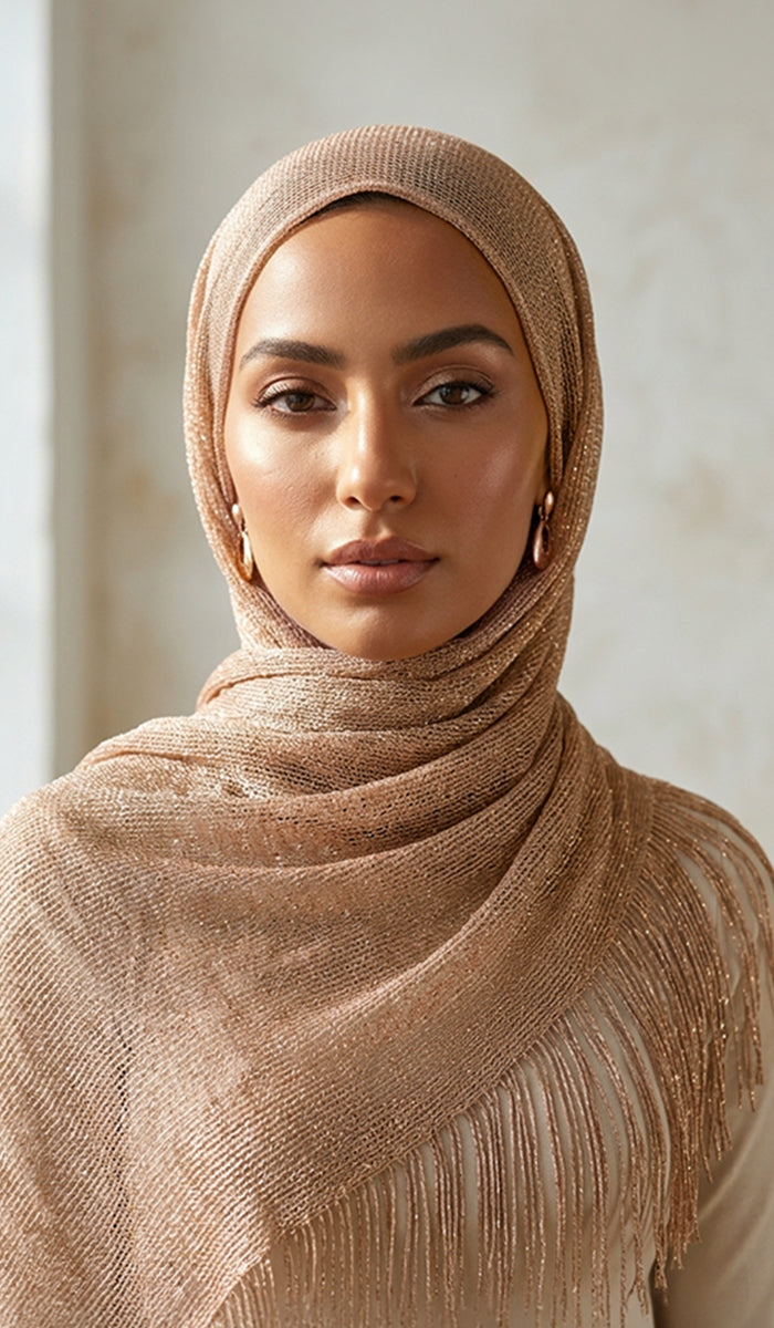 Woman wearing a beige hijab with fringe details against a neutral background