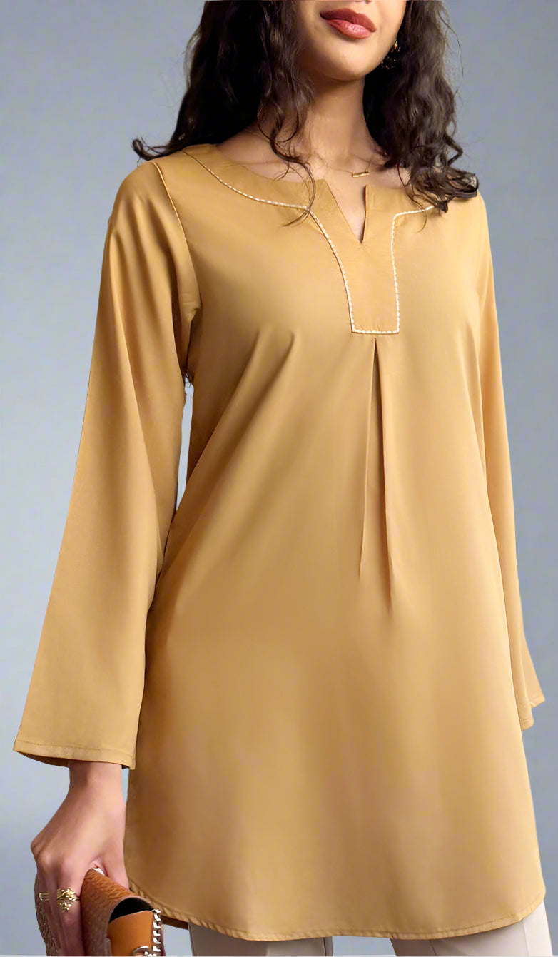 Woman wearing a mustard yellow long-sleeve top against a neutral background
