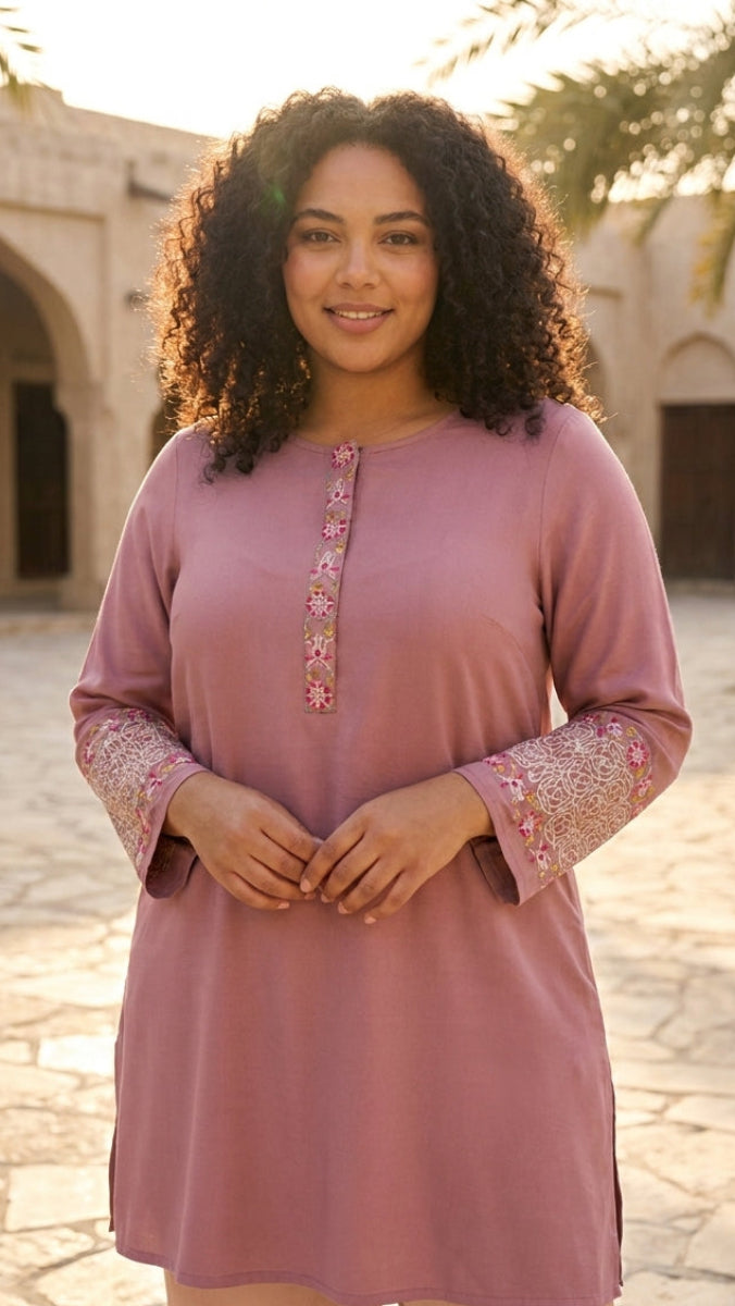 Woman wearing a pink dress with floral patterns in an outdoor setting