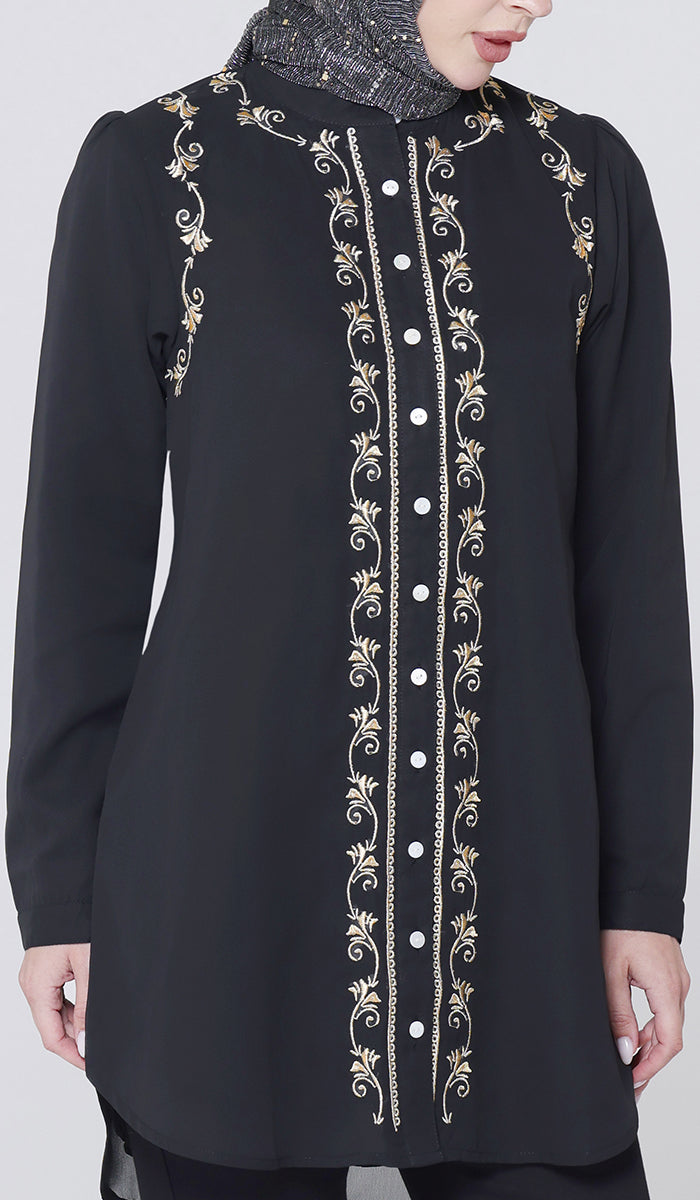 Black embroidered dress with gold detailing on a white background