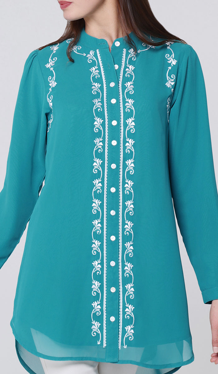 Teal embroidered blouse on a plain background