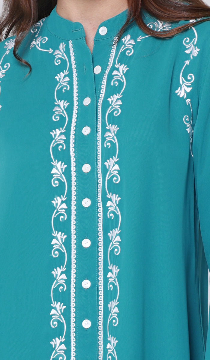Teal shirt with white embroidery details on a plain background