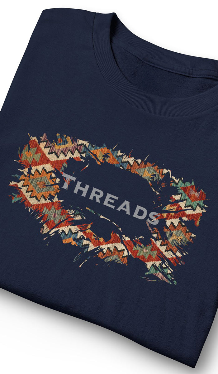 A folded navy blue t-shirt featuring a colorful geometric patterned graphic that spells out 'THREADS' in white text.