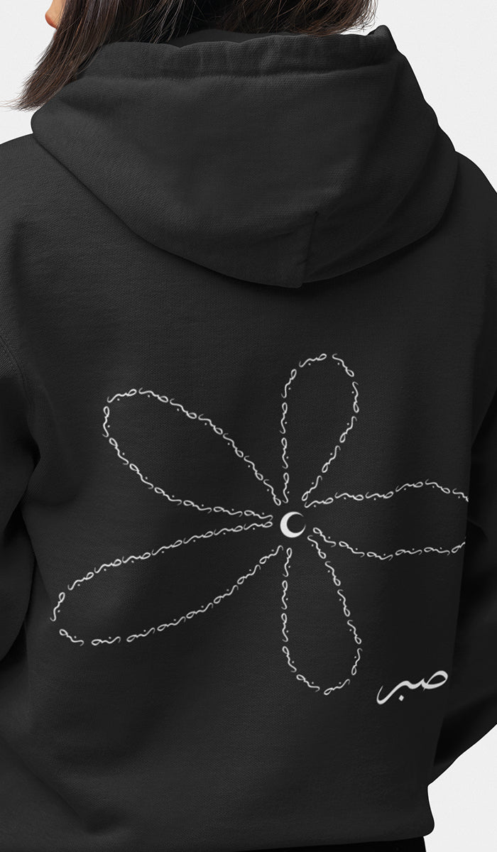 Black hoodie with a white floral design on the back against a gray background