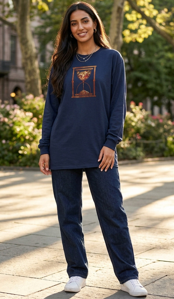 A woman modeling a navy blue long-sleeve graphic sweatshirt and matching navy blue jeans, standing outdoors on a paved walkway with trees and flowers in the background.
