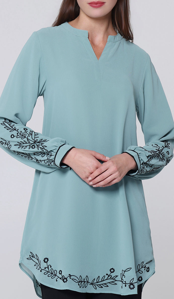 Light blue long-sleeve top with floral embroidery on a plain background