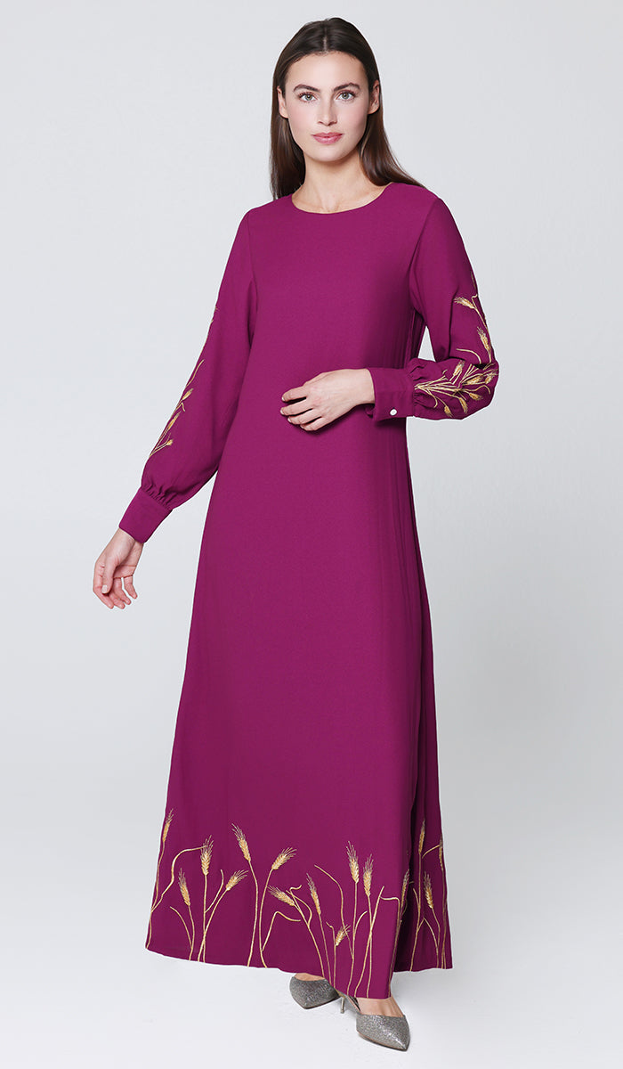 Woman wearing a long purple dress with floral patterns on a white background