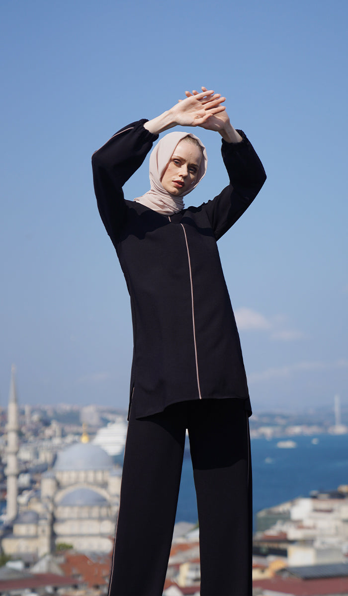 Woman standing on rooftop wearing Abiyya set in Black/Cafe. 
