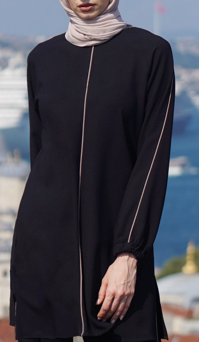 Woman outside wearing Abiyya tunic in Black/Cafe. 