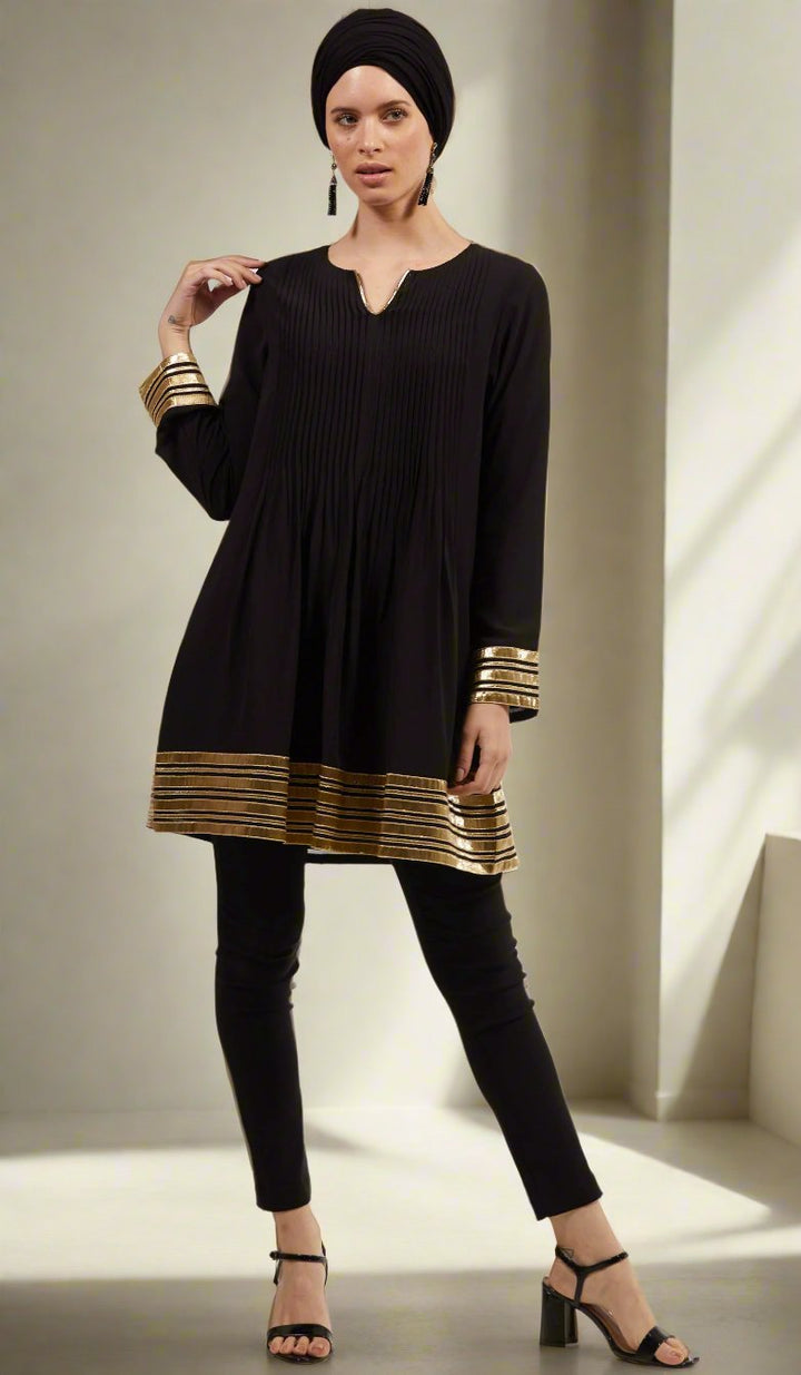 Woman wearing Sultana tunic in Black with black pants and heels. 