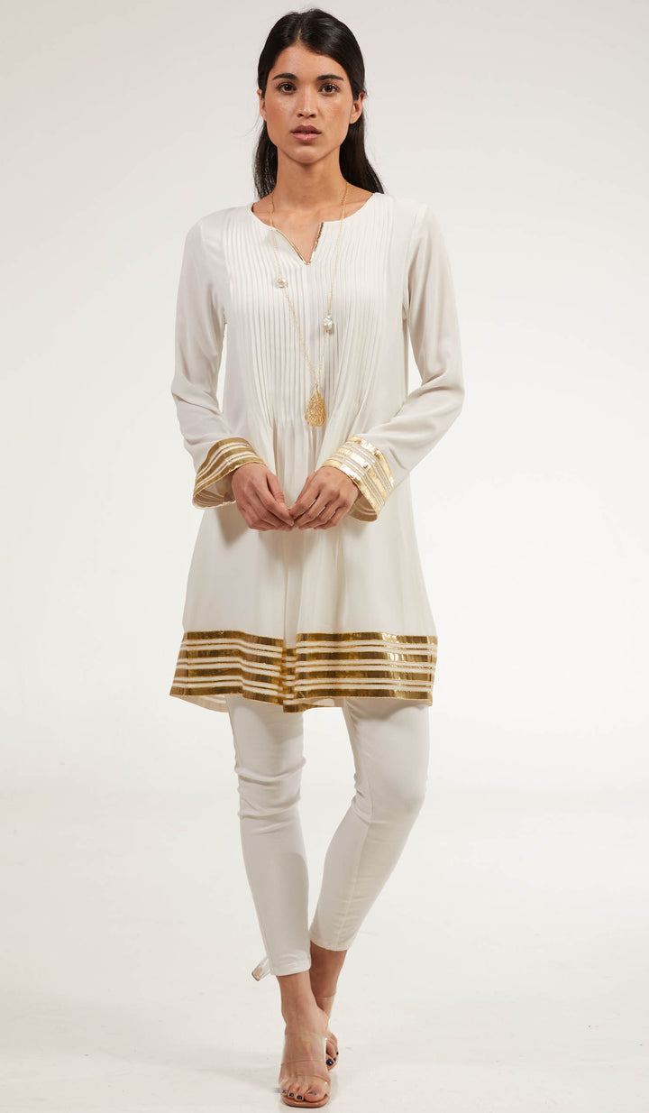 Woman wearing Sultana tunic in Off White with white pants and heels. 
