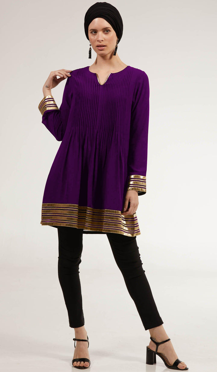 Woman with hand on her shoulder wearing Sultana tunic in Deep Plum with black pants and heels. 