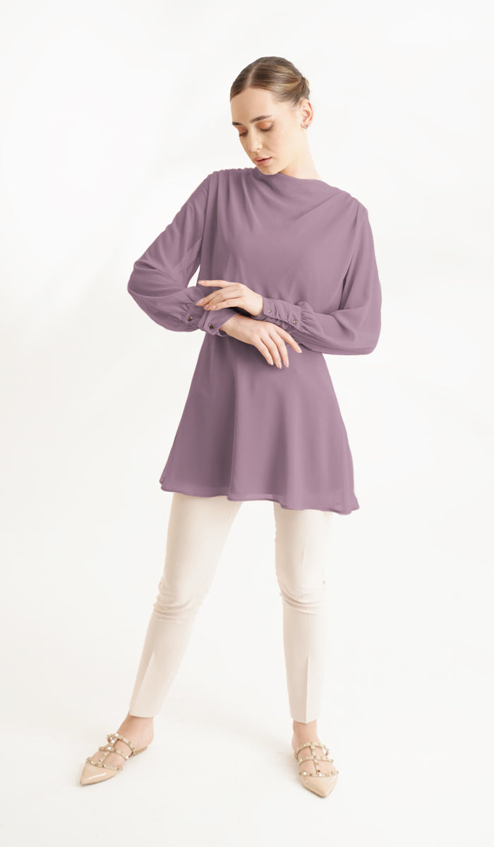 Woman looking at sleeve of the Myra tunic in Dusty Mauve. 