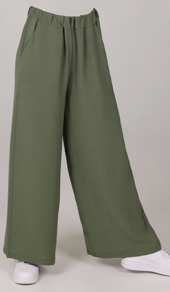 Woman wearing Tina pants in Olive with sneakers. 